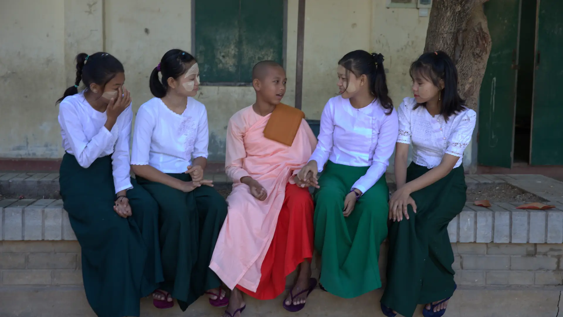 A row of seated, smiling adolescent Burmese girls