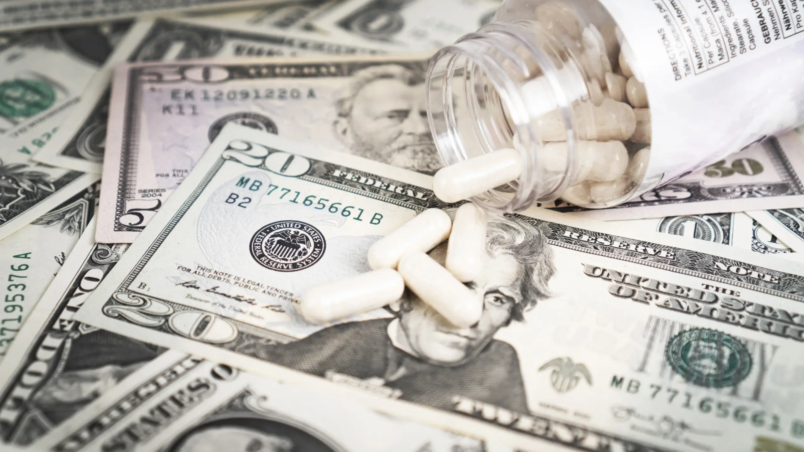 Dollar bills with pills spilling over them