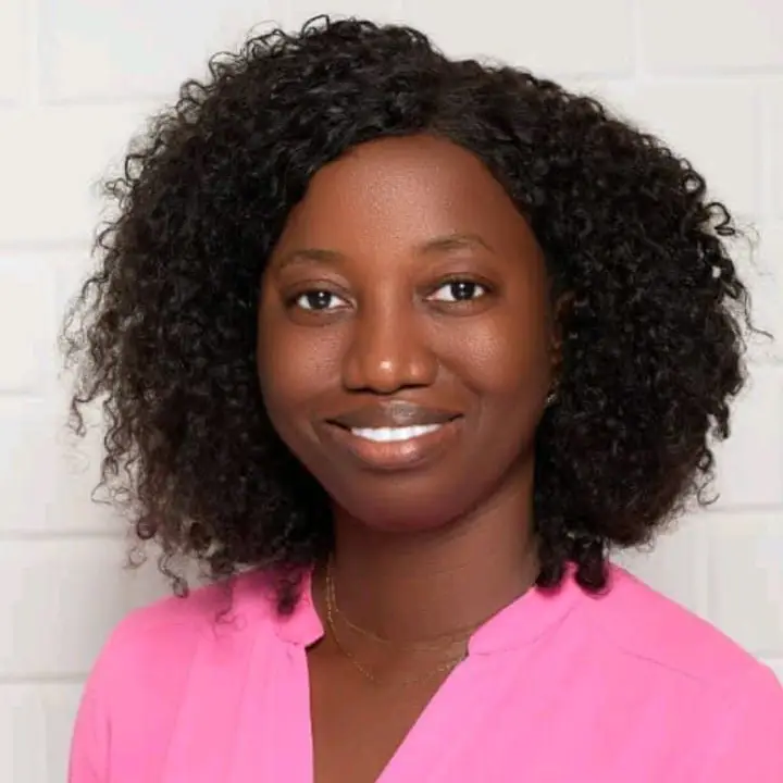 Headshot of a smiling Sierra Leonian woman with curly hair and a pink top