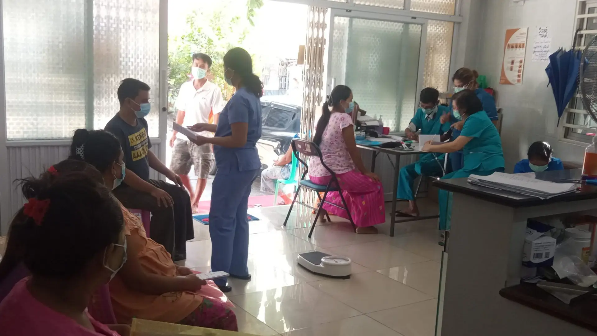 A health facility waiting room and reception in Myanmar. Everyone is wearing a face mask.