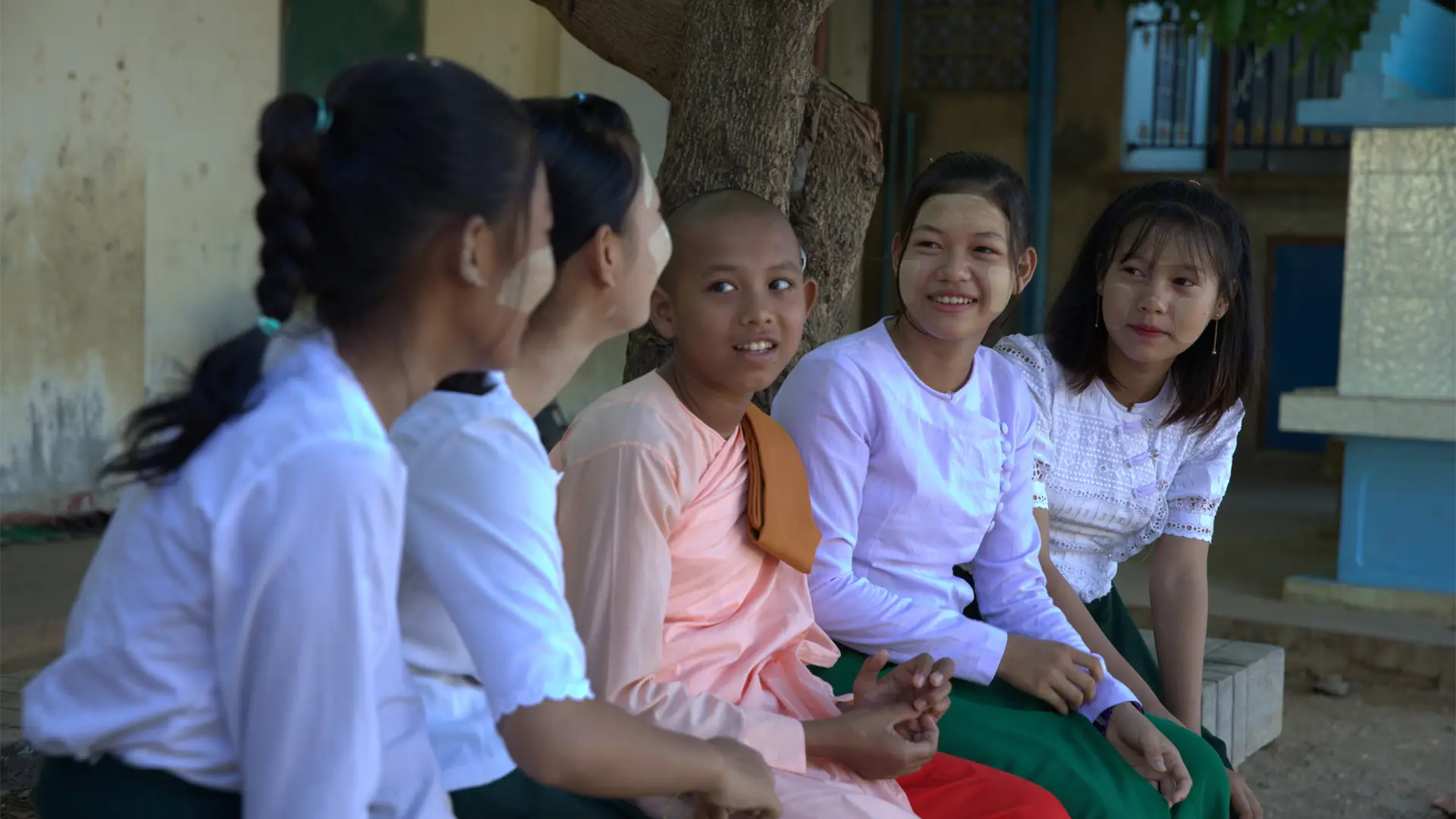A row of seated, smiling adolescent Burmese girls