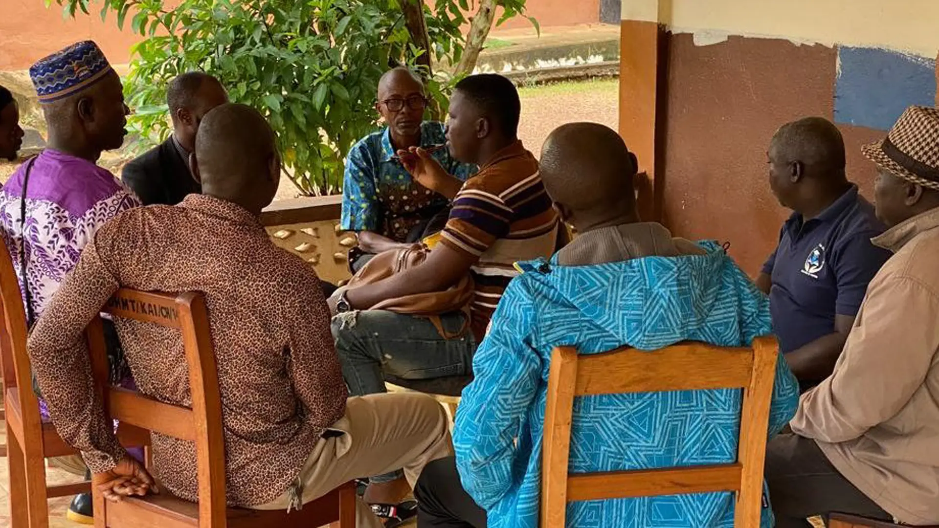A group of men sit talking together outside a building in Sierra Leone