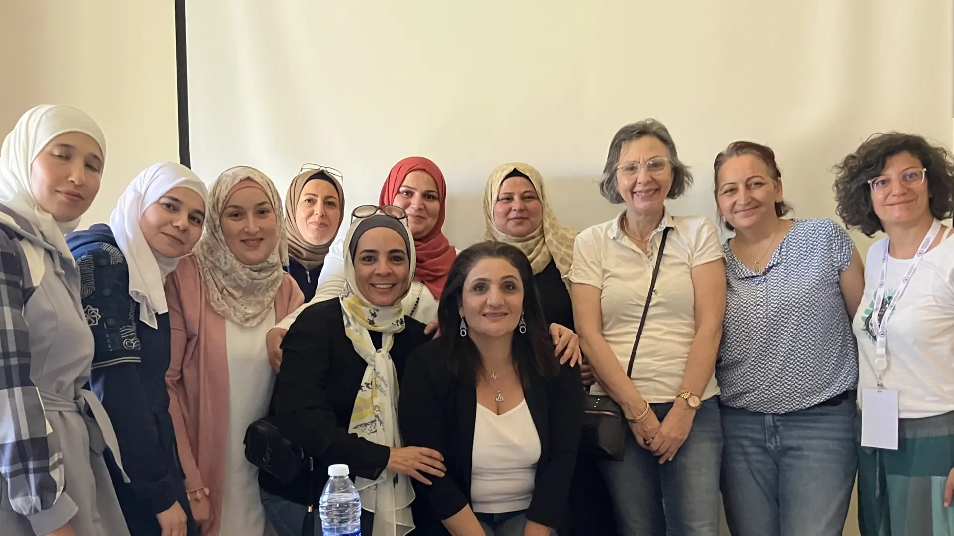 A row of smiling Syrian and Lebanese women - most wearing headscarves