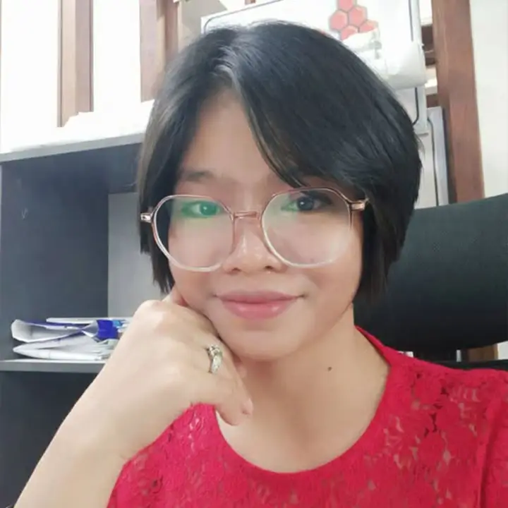 headshot of a smiling young Burmese woman with short black hair and glasses