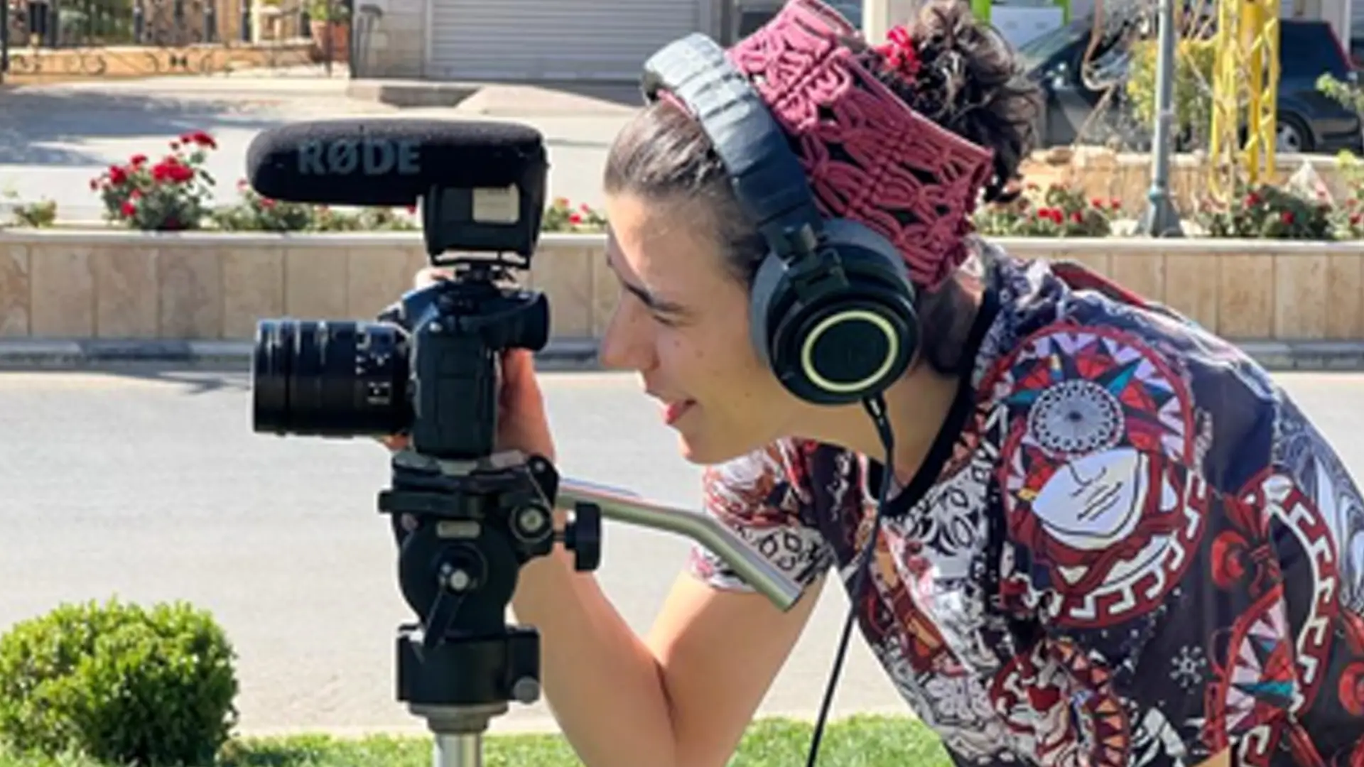 A Lebanese woman wears headphone and looks into the view finder of a camera on a tripod