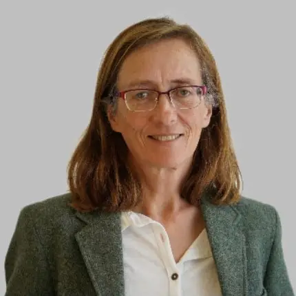 A headshot of a smiling European woman in a jacket and wearing glasses